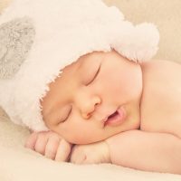 adorable baby wearing white hat sleeping tight