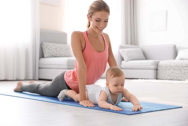smiling mother doing yoga with baby at home