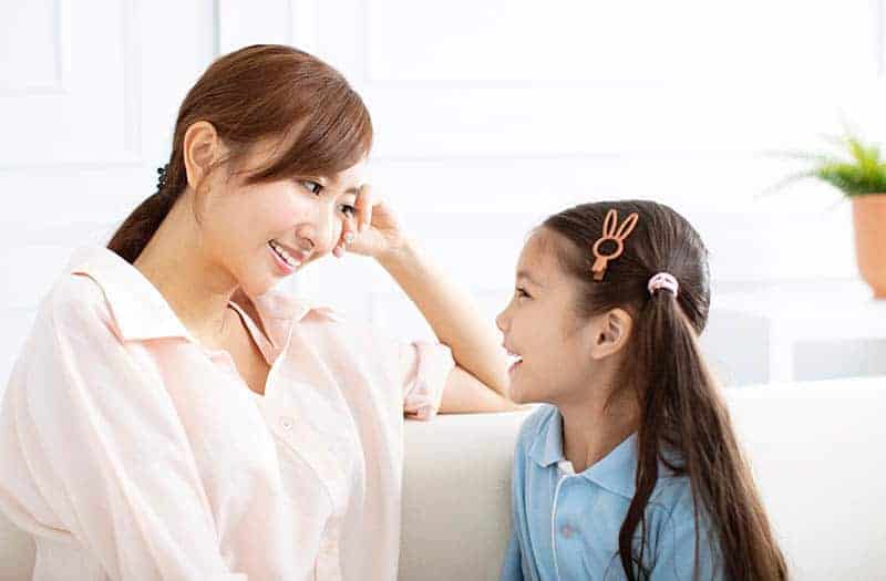 smiling mother looking and listening to her cute daughter