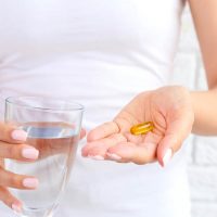woman holding lecithin pill and glass of water