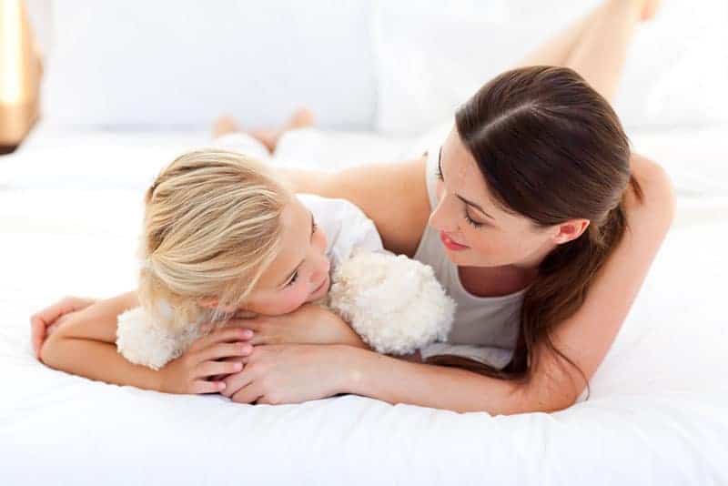 sweet mother and daughter talking on the bed