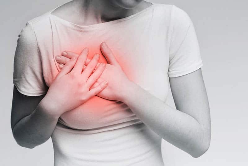 woman feeling breast pain and touching her chest with hands