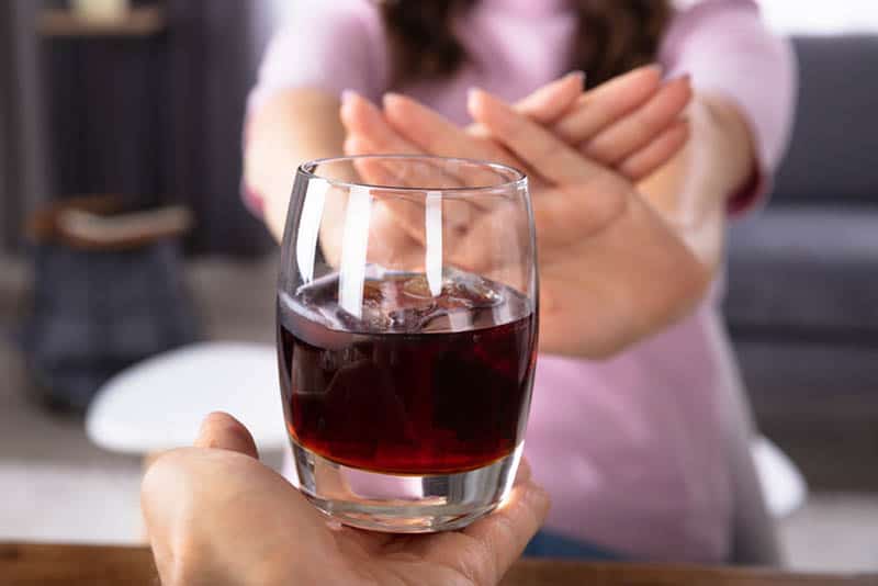 woman refusing a glass of alcohol in the house