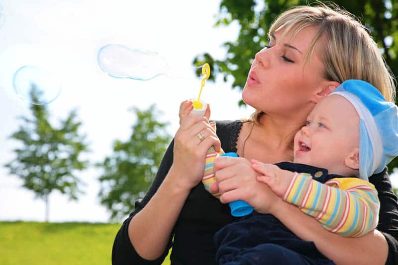 young mother blowing bubbles with her cute baby