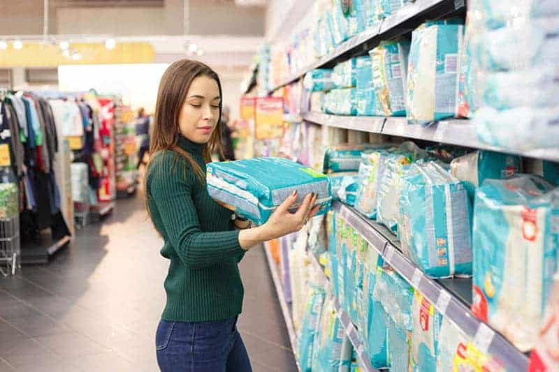 young mother in store buying pampers diapers