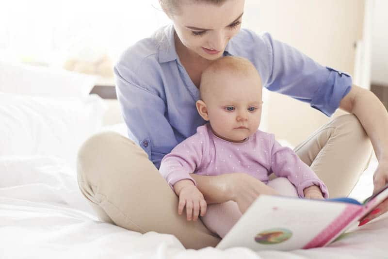 young mother reading a book to her baby