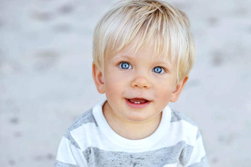 adorable little boy with blue eyes and a blue hair smiling
