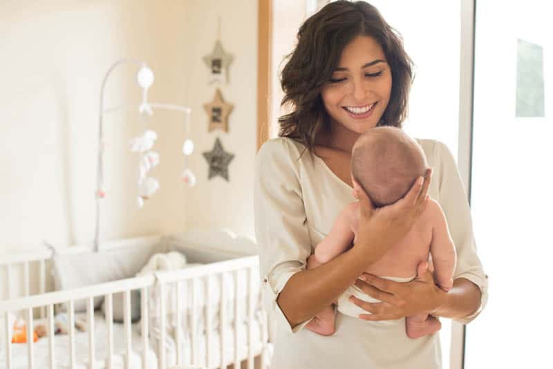 beautiful woman holding her baby and looking at her with smiling face
