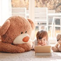 cute little boy watching cartoons on the floor with teddy bears