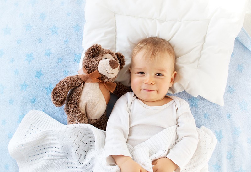 cute baby boy lying on the bed with teddy bear