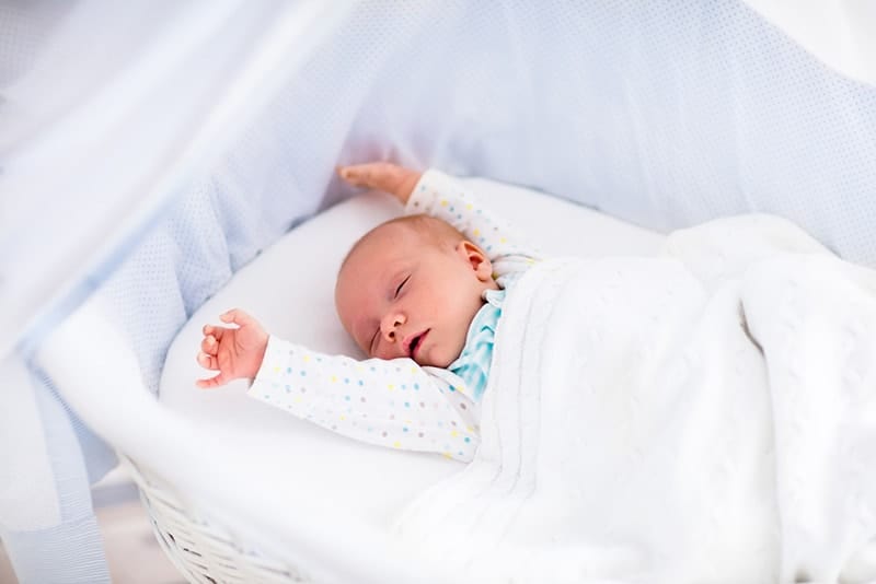 cute baby sleeping with hands up in the crib