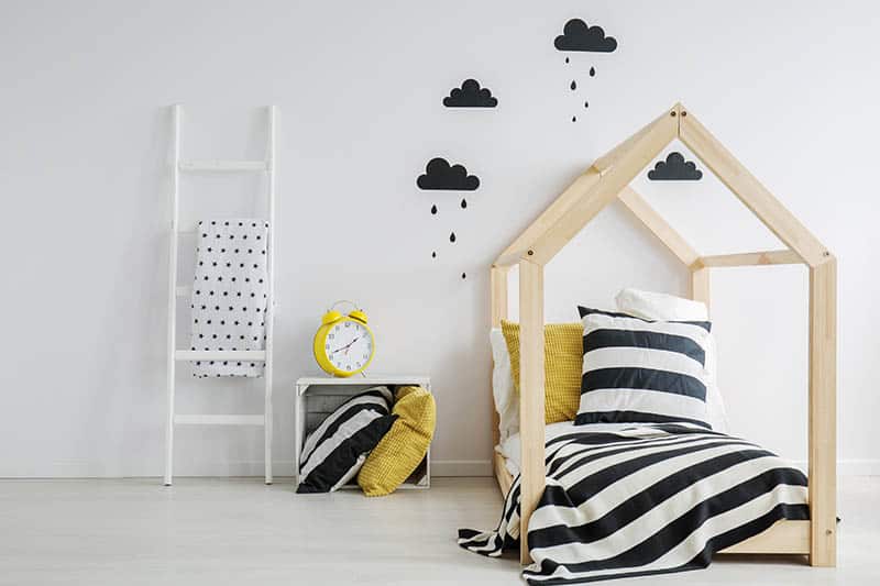 cute toddler bed with interesting wall with black clouds on it 