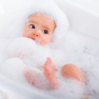 cute baby taking a bath covered with bubbles