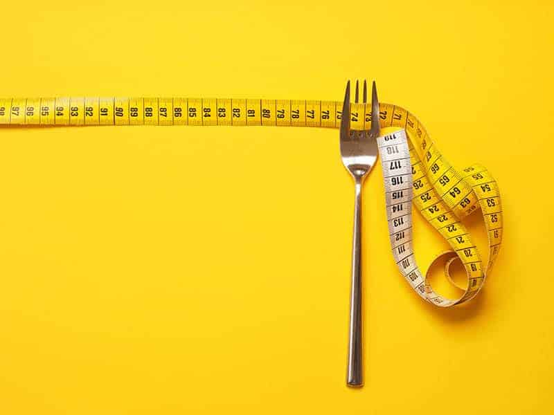 fork and measuring tape on a yellow background