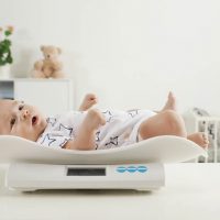 cute baby being weighed on a scale at home