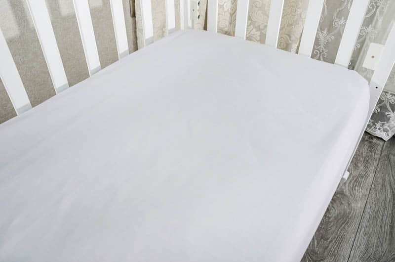 mattress with white sheet on in the toddler bed in the bedroom
