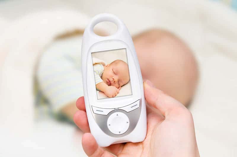 mother holding video baby monitor with baby image while baby sleeps