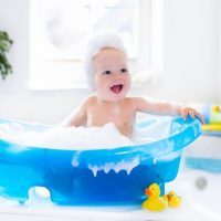 happy baby taking a bubble bath with rubber ducks