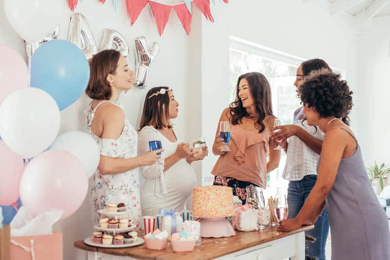 pregnant woman celebrating baby shower with friends at home 