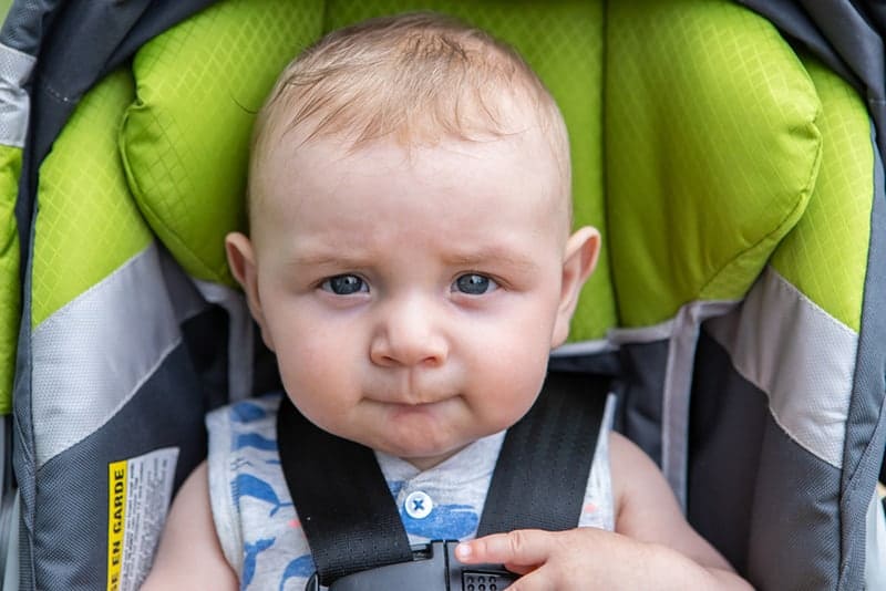 sweet baby boy sitting in a stroller and sucking his lip