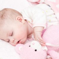 adorable baby girl sleeping with pink teddy bear