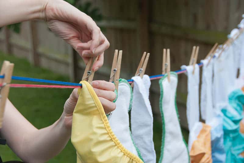 woman hangs cloth diapers on a clothesline to dry in the sun