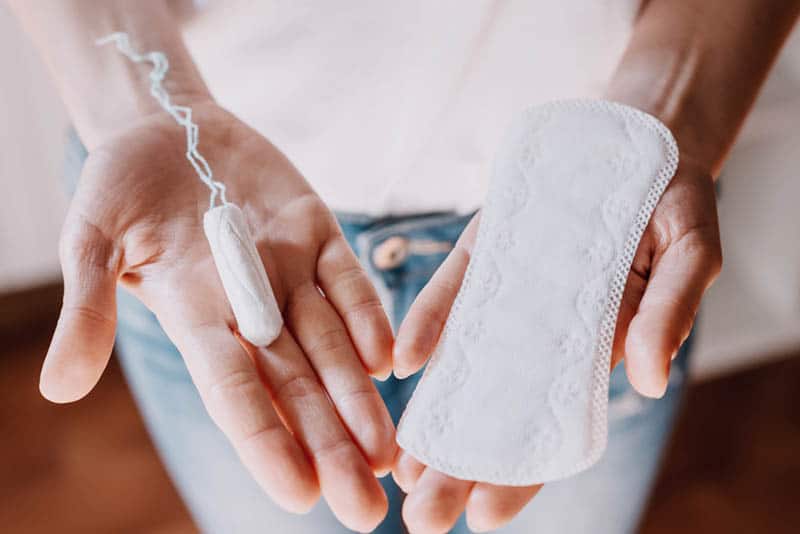 woman holding a tampon in one hand and the hygiene pad in the other hand