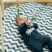 baby playing on the floor with a wooden gym