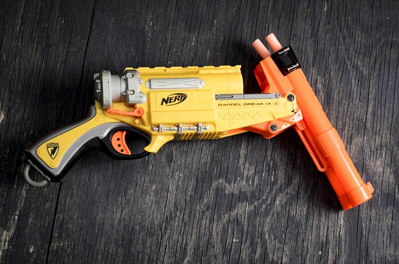 yellow nerf dart gun with foam bullets on black wooden table