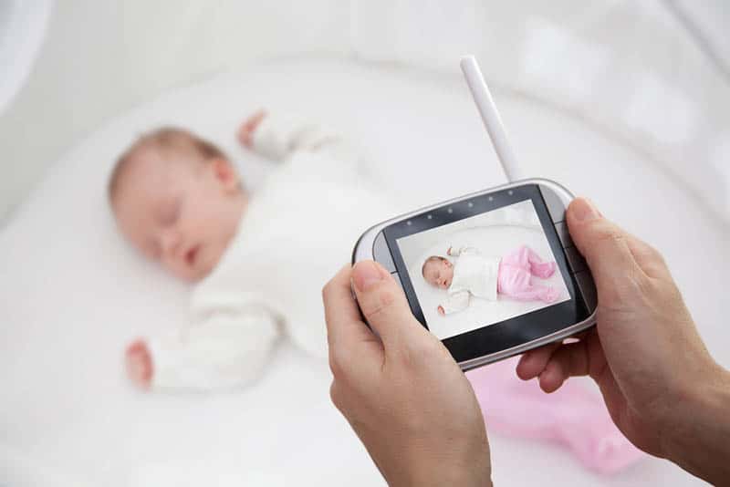 young father holding baby monitor while baby sleeping beacuse of security reasons