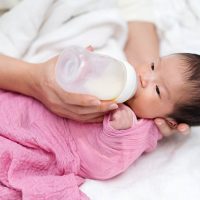 mother feeding her newborn baby with a bottle of milk