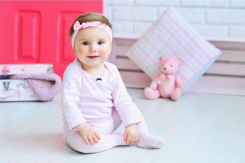 adorable girl wearing pink clothes and trendy headband while posing for a photo