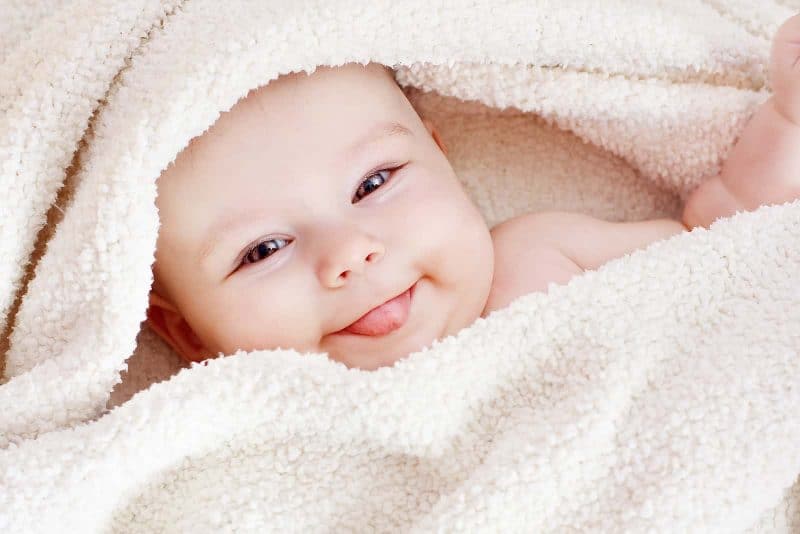 baby smiling while being wrapped up in a towel