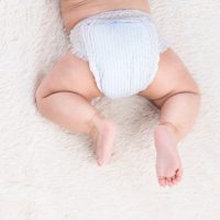 adorable baby in diapers lying on tummy on the bed