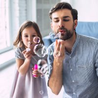 father and daughter playing with bubbles