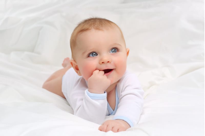 Baby with bright blue eyes in white bed