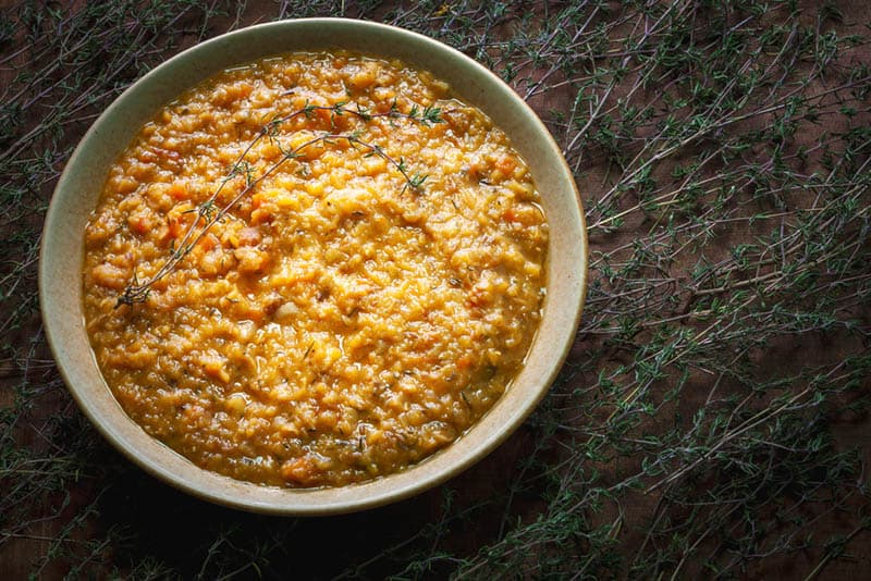 Bowl with red lentil and dried apricot soup with thyme herb