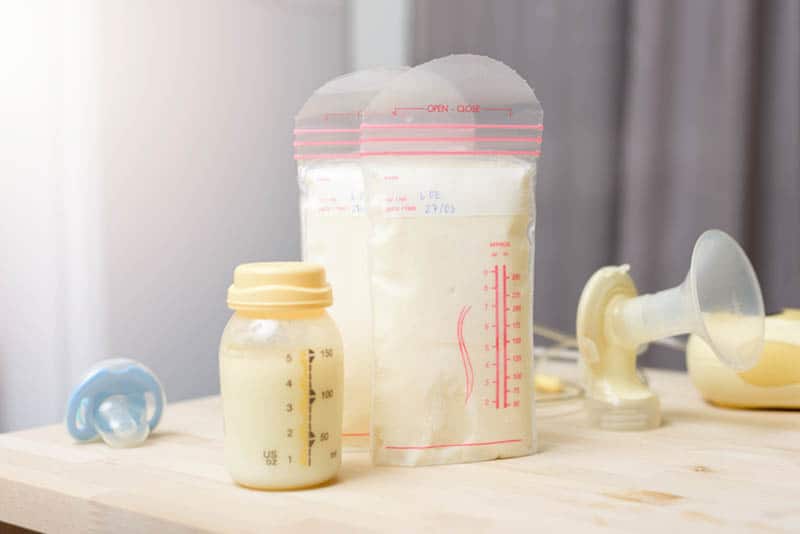 Breast milk frozen in plastic storage bags with bottle and pacifier on the table