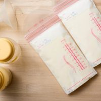 two storage bags of breast milk with pump and bottles on the table