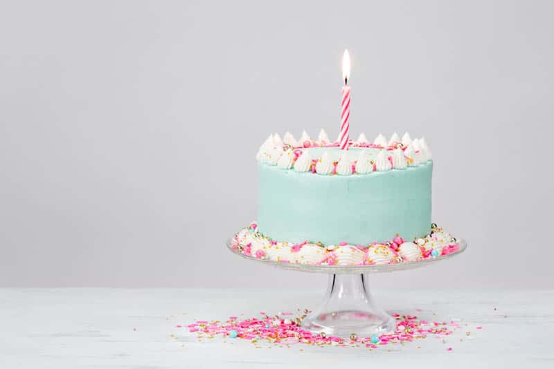 Pastel blue birthday cake with pink sprinkles on the table