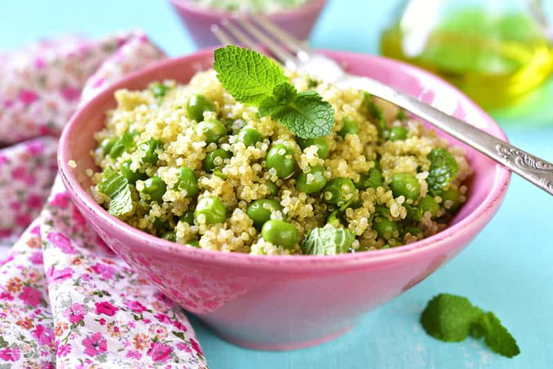 Quinoa salad with green pea and mint in the pink bowl with colorful cloth