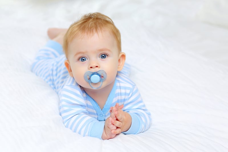 charming blue-eyed baby 7 month old lies in bed 