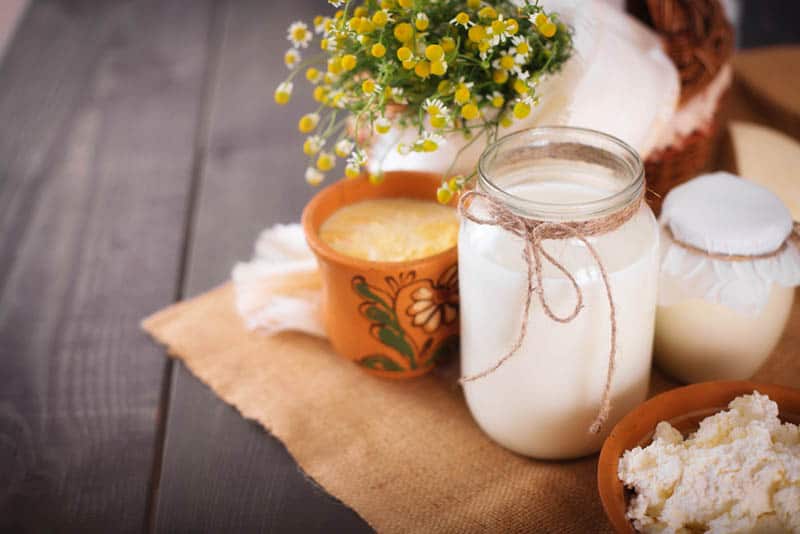 a jar of goat's milk with cheese and yogurt on the table with flowers