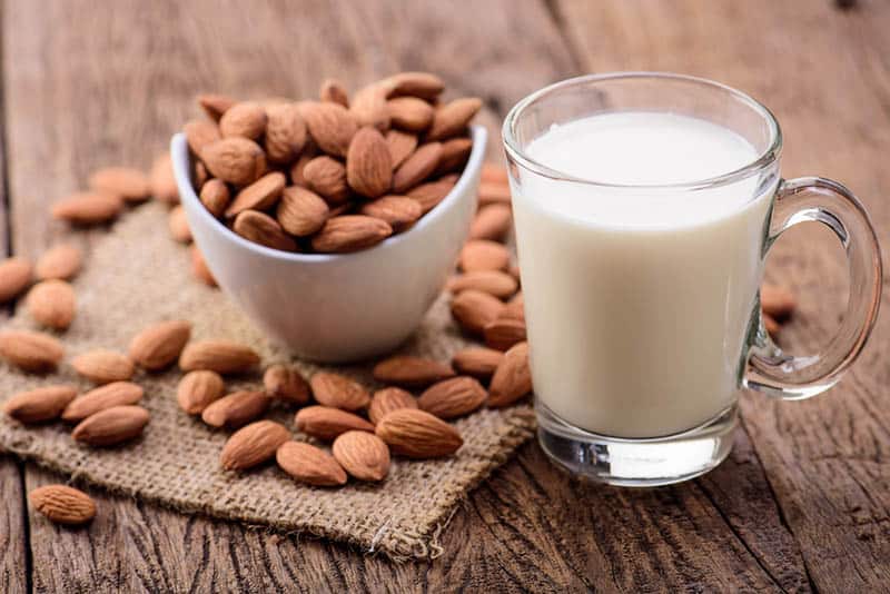 almond milk in glass with almonds on the wooden table
