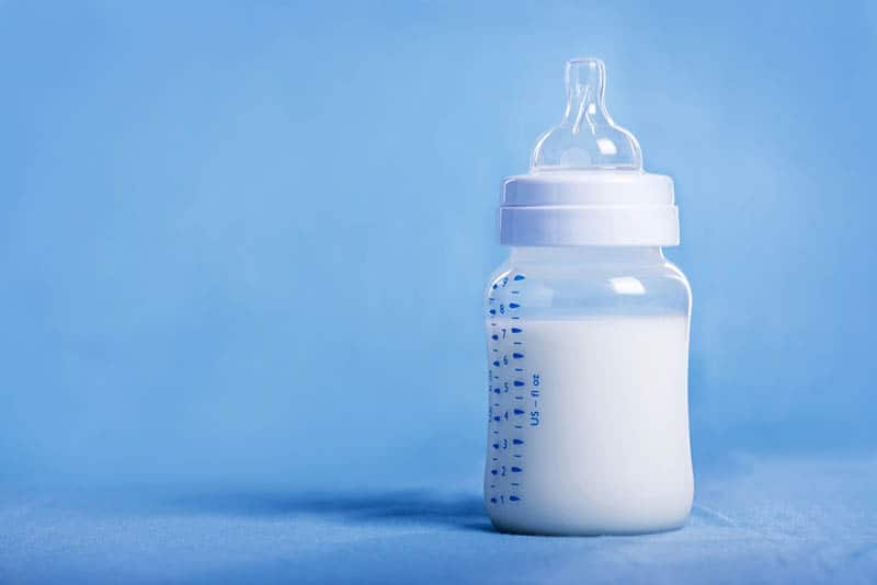 baby bottle full of milk for baby on the table covered with blue sheet