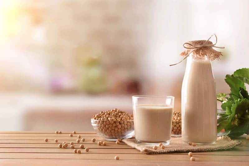bottle and glass of soy milk with grains on the wooden table