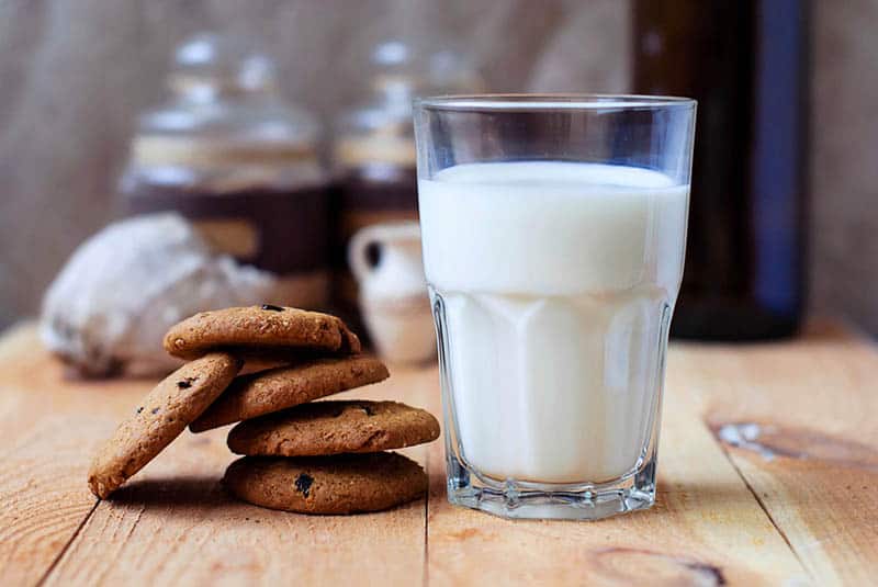 breakfast oatmeal cookies with raisins and a glass of milk on a wooden table
