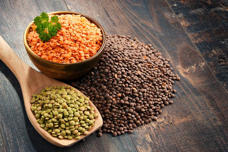 colorful lentils in a bowl and spoon on the wooden table