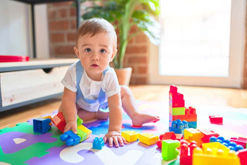 cute baby boy playing on the floor with toys