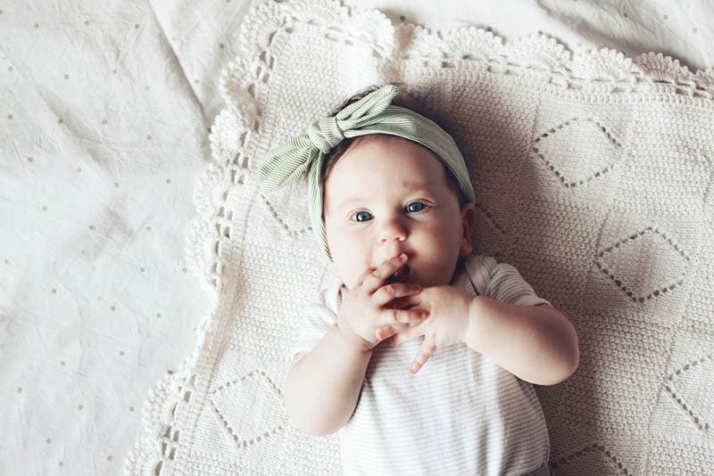 cute baby girl wearing headband lying on the crochet blanket